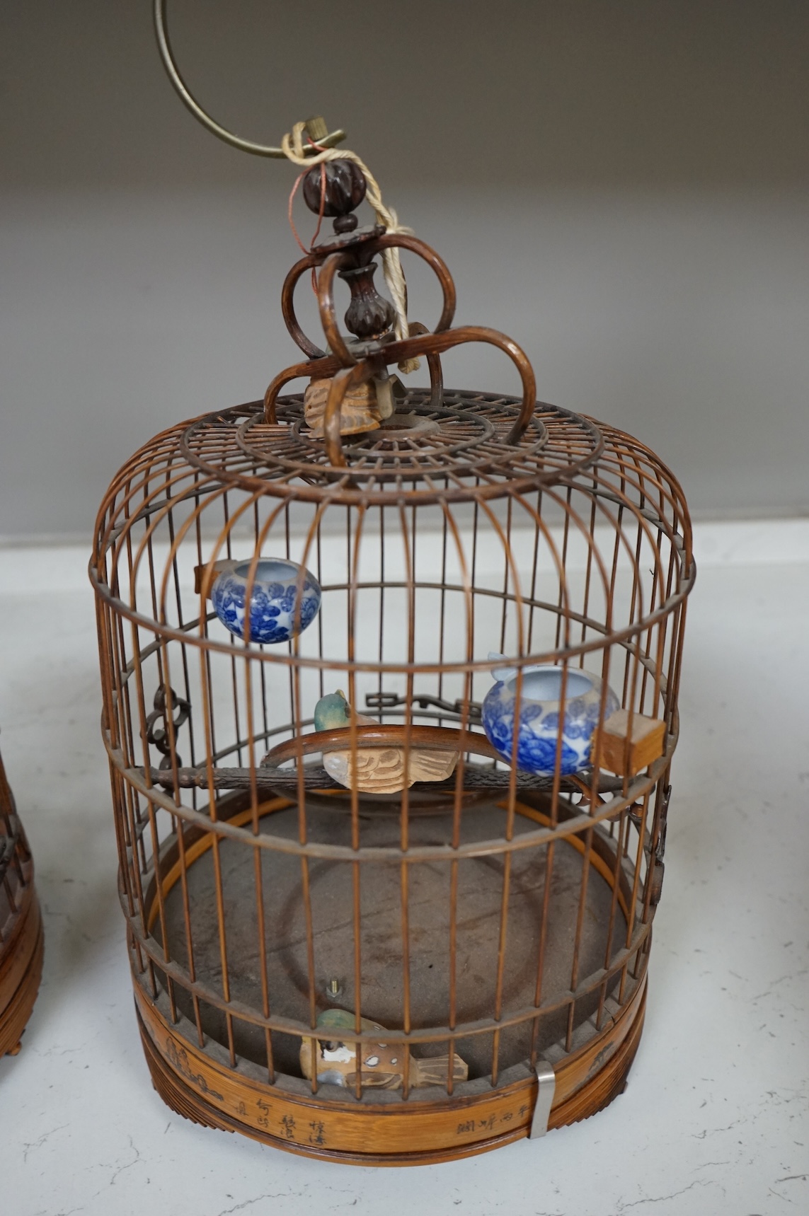 A pair of Chinese bamboo and metal birdcages with blue and white feeders. 34cm high not including hook